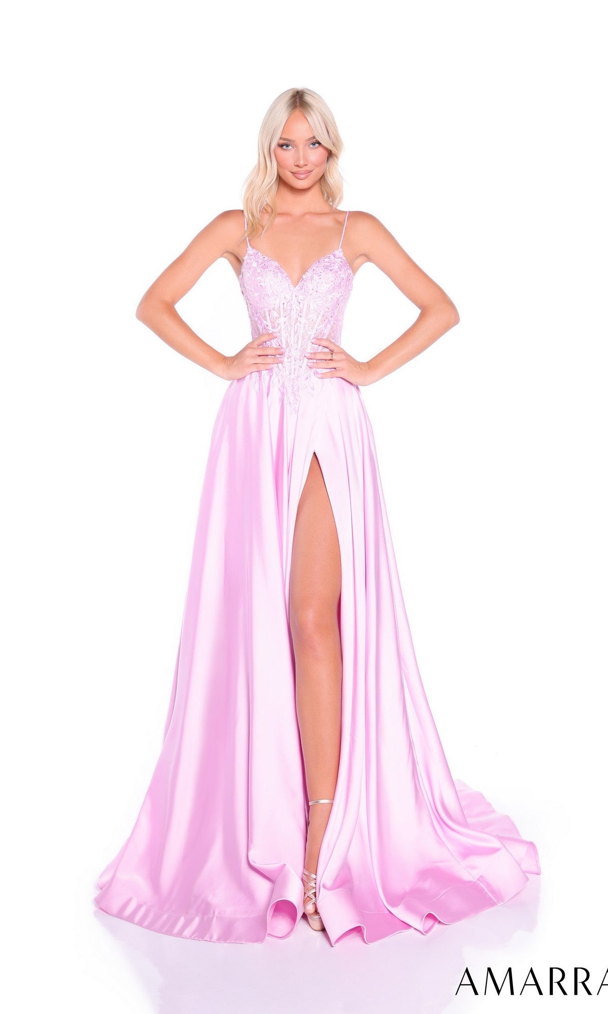 A woman wears the Amarra 89517, a light pink long prom dress featuring a sleeveless lace corset bodice and high-leg slit, standing against a white background.